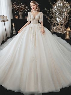 a woman in a wedding dress standing next to a window with her hands on her hips