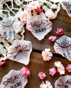 some pink flowers are laying on a wooden table with lace doily that says dream baby