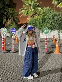 a woman standing in front of orange and white traffic cones with her hands on her head