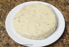 a white plate topped with a piece of food covered in plastic on top of a counter