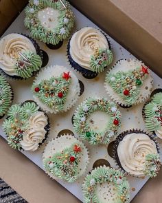 twelve cupcakes with frosting and christmas decorations in a box on a table