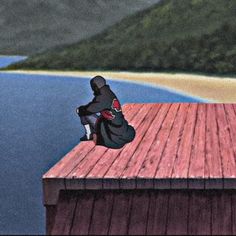 a person sitting on top of a wooden dock next to the ocean with mountains in the background