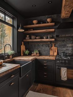 a kitchen with black cabinets and wooden shelves on the wall, along with wood flooring