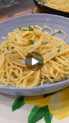 a blue plate topped with pasta and parsley on top of a yellow table cloth