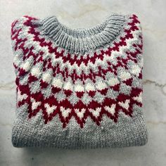 "A warm, chunky-knit pullover style sweater with a lovely geometric pattern around the yoke. It's a soft grey with white and burgundy/red. This sweater was worked bottom-up in the round to the underarm, the sleeves were worked separately, and then all parts were joined together on one needle to the yoke and neck opening. Likely a large, but please see details below. The measurements are taken while the sweater is laying flat. Measures:  20\" (51 cm) across shoulders (roughly, as the shoulders slope)  26\" (66 cm) across chest 31\" (78.75 cm) from front neck to hem 18\" (45.75 cm) from underarm to end of sleeve 52\" (132 cm) around at bottom hem" Gray Nordic Sweater For Fall, Cozy Gray Chunky Knit Pattern, Knitted Nordic Patterns For Fall, Nordic Knitted Patterns For Fall, Gray Fair Isle Sweater For Fall, Nordic Style Chunky Knit Sweater, Nordic Chunky Knit Sweater, Cozy Knit Patterns For Winter, Cozy Winter Knit Patterns