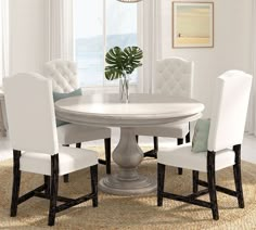 a dining room table with white chairs and a potted plant on the top of it