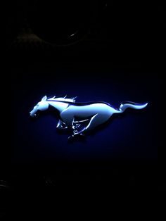 a blue neon sign with a white horse on it's side in the dark