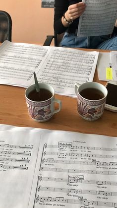 two cups of coffee sit on a table with sheet music