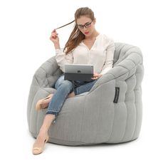 a woman sitting in a bean bag chair with her laptop on her lap and looking at the screen