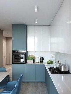 a modern kitchen with blue chairs and white counter tops, along with an oven on the wall