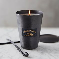 a candle that is sitting on a table next to some spoons and an object