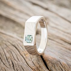 a wedding ring with a diamond in the center on a piece of wooden planks