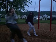 two girls playing on a swing set at dusk