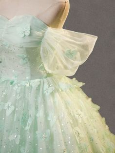 Celebrate elegance in this Mint Green Evening Dress, designed to exude sophistication and grace at every turn. Crafted from layers of soft, mint green tulle, this gown is adorned with exquisite floral appliqués that cascade down its length, adding depth and enchantment to the fabric's gentle flow. The bodice features a structured corset that cinches at the waist, creating a flattering silhouette that celebrates the fullness of plus-size figures. This corset is not only a nod to classic style but also ensures a perfect, tailored fit, enhancing comfort and confidence. The dress's romantic off-shoulder design, complemented by airy butterfly sleeves, frames the neckline beautifully, adding a touch of delicate charm. Flowing effortlessly to a floor-length finish, the skirt swirls with every ste Fitted Green Organza Ball Gown, Spring Green Evening Dress For Wedding, Green Organza Evening Dress For Prom, Spring Green Wedding Evening Dress, Green Spring Wedding Evening Dress, Spring Wedding Green Ball Gown, Green Tulle Evening Gown, Green Tulle Evening Dress With Ruffles, Green Ball Gown With Sweetheart Neckline For Formal Events