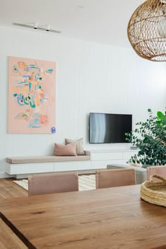 a living room filled with furniture and a flat screen tv mounted on the wall above a wooden table