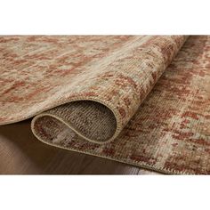 an orange and beige rug on top of a wooden floor