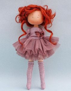 a doll with red hair wearing a pink dress