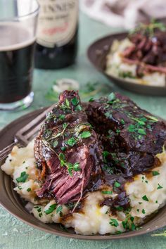 a plate topped with mashed potatoes covered in beef and gravy next to a glass of beer