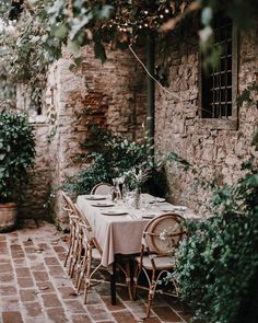 an outdoor dining area with tables and chairs, surrounded by greenery on either side of the building