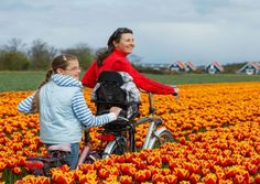 two girls are riding bikes through a field of tulips