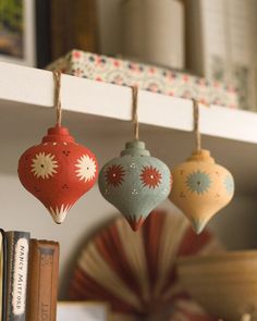 three ornaments hanging from hooks on a shelf next to an open bookcase with books