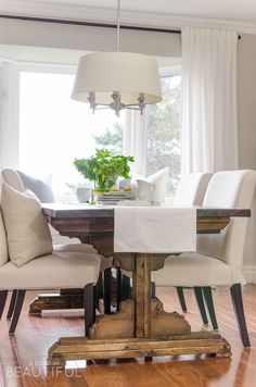 a dining room table with white chairs and a potted plant on top of it