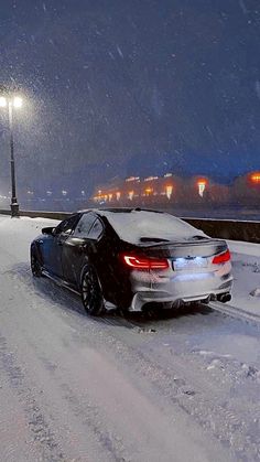 a car is parked on the side of a snowy road in front of a street light