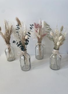 four vases with dried flowers and plants in them