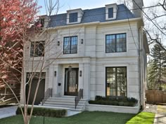 a white two story house with black shutters on the front and side windows, grass in front