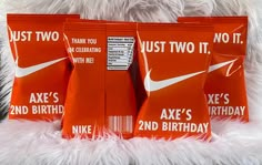 three red nike birthday bags sitting on top of a white fur covered bed next to each other