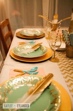 the table is set with gold and green plates, silverware, and napkins