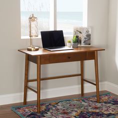 a laptop computer sitting on top of a wooden desk in front of a large window