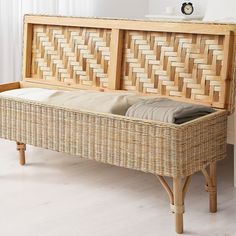 a wicker bench with folded linens in it