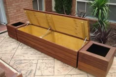 a large wooden box sitting on top of a stone floor next to a planter