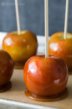 caramel apples with toothpicks in them on a tray