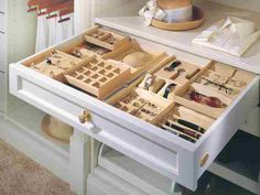 an open drawer in a white cabinet filled with lots of jewelry and other items on it