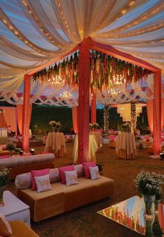 an outdoor wedding setup with couches, tables and chandeliers on the ceiling