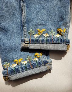 two jean pants with daisies embroidered on them