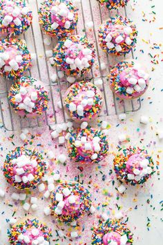 sprinkle covered cupcakes on a cooling rack with sprinkles