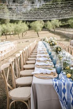 a long table is set with blue and white linens for an outdoor dinner party