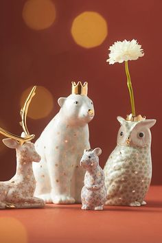 three ceramic figurines in the shape of animals with a flower on their head