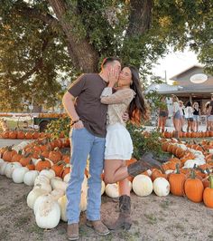 a man and woman kissing in front of pumpkins