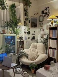 a living room filled with lots of plants next to a laptop computer on top of a table