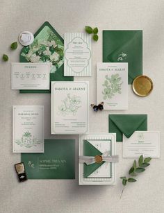 the wedding stationery is laid out on top of each other, including green envelopes and