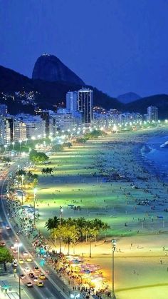 the beach is lit up at night with cars driving on it and people walking around