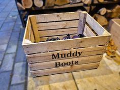 a wooden crate filled with shoes sitting on top of a stone floor next to firewood