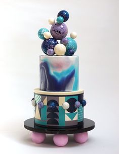 a multi - tiered cake decorated with marbles and balls on a black stand