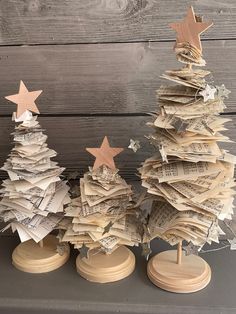 three small wooden christmas trees made out of old sheet music sheets, with stars on them