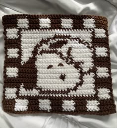 a brown and white crocheted square with sheep on it