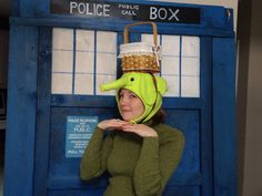 a woman in a green dress and hat standing next to a tardist box